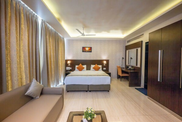 A hotel room with a bed, a sofa, a desk, and a mirror.