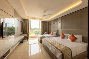 A hotel room with a bed, a desk, a TV, and a view of the outdoors. - Fortune Plaza hotel (Udupi)