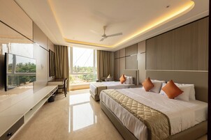 Habitación de hotel con cama, escritorio, televisión y vistas al exterior.