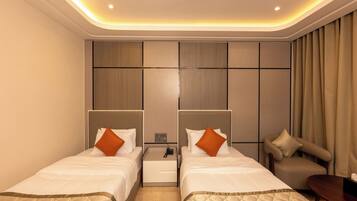 Habitación de hotel con dos camas, una mesita, un sofá y una mesita de noche con un teléfono.