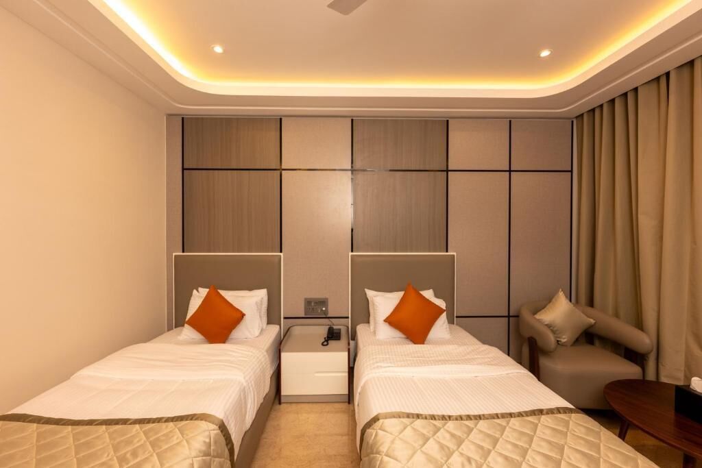 Een hotelkamer met twee bedden, een bank, een klein tafeltje en een nachtkastje met telefoon.