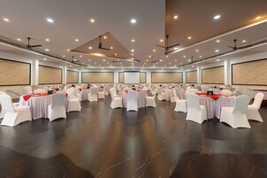 Un salón de conferencias con filas de mesas y sillas, ventiladores de techo e iluminación empotrada.