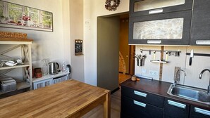 Moderni keittiö, jossa on puinen pöytä, mustat kaapit ja raidallinen matto.