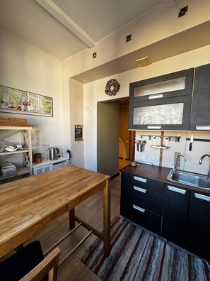 Una cocina moderna con una mesa de madera, armarios negros y un tapete a rayas.