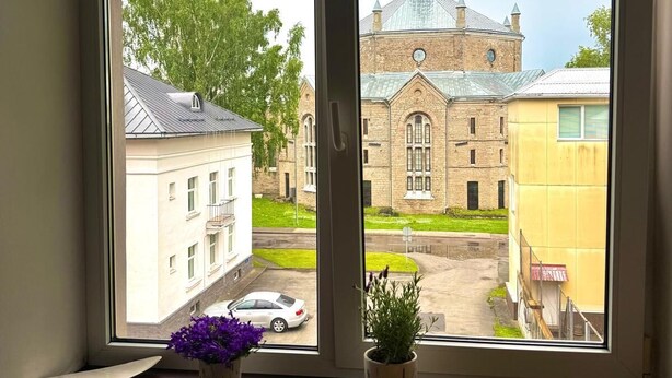 Huone, jossa on suuri ikkuna, josta avautuu näkymä kirkolle ja kadulle.