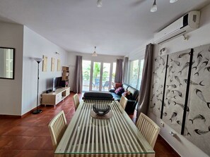 A spacious living area with a large dining table, a sofa, a TV, and a view through the glass doors. - The Breathtaking Views - Kotorscapes II (Muo)