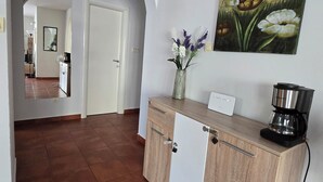 A hallway with a kitchen area, a coffee maker, and a painting on the wall. - The Breathtaking Views - Kotorscapes II (Muo)