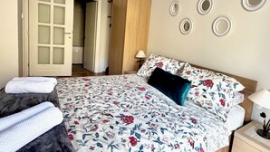 A bedroom with a bed, a nightstand, a lamp, a door, and a wall with circular decorations. - The Breathtaking Views - Kotorscapes II (Muo)