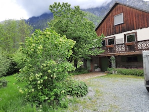 A rustic wooden house with a balcony, surrounded by lush greenery and mountains in the background. - Chalet Le Petit Catelan 5p-9p at 5 min to Ski-lift Eau d'Olle Expres (Le Bourg-d'Oisans)