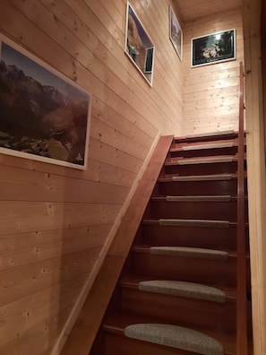 A wooden staircase with carpeted steps leading to a landing with framed pictures on the walls. - Chalet Le Petit Catelan 5p-9p at 5 min to Ski-lift Eau d'Olle Expres (Le Bourg-d'Oisans)