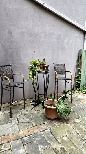 Eine Terrasse mit zwei Stühlen, einem Tisch und Kübelpflanzen.