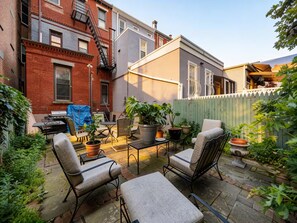 A patio with outdoor furniture, potted plants, and a barbecue grill. - Brownstone Charm • 8 Min to NYC & MetLife • Parkings • Backyard • BBQ (Weehawken Township)