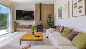 Una sala de estar con sofá, mesa de centro, televisor, pared de paneles de madera y chimenea.