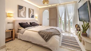 Un dormitorio moderno con una cama grande, lámparas de noche, un televisor y vistas al exterior.