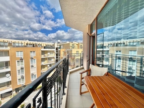 A balcony with a wooden table and chairs, a black railing, and a view of neighboring apartment buildings. - Marvelous 1-bedroom hotel with AC in sunny Sunny Beach 100 meter to the beach (Sunny Beach)