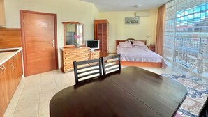Quarto com cama, penteadeira, televisão, cadeira e mesa.