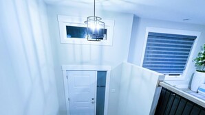 A staircase with a wooden handrail, a white door, and a window with blinds. - Wonderful 3-bedroom Full House Near Magnetic Hill (Moncton)