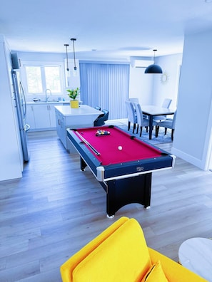 A modern living space with a pool table, a dining area, and a kitchen. - Wonderful 3-bedroom Full House Near Magnetic Hill (Moncton)