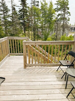 A wooden deck with a railing, a chair, and a table. - Wonderful 3-bedroom Full House Near Magnetic Hill (Moncton)