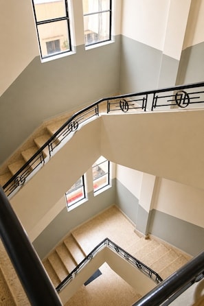 A multi-level interior with a central staircase, multiple windows, and a view of the outside. - 1-bedroom aptmt in Armenia, Mar Mkhayel street, spacious bathroom 2 balconies (Beirut)