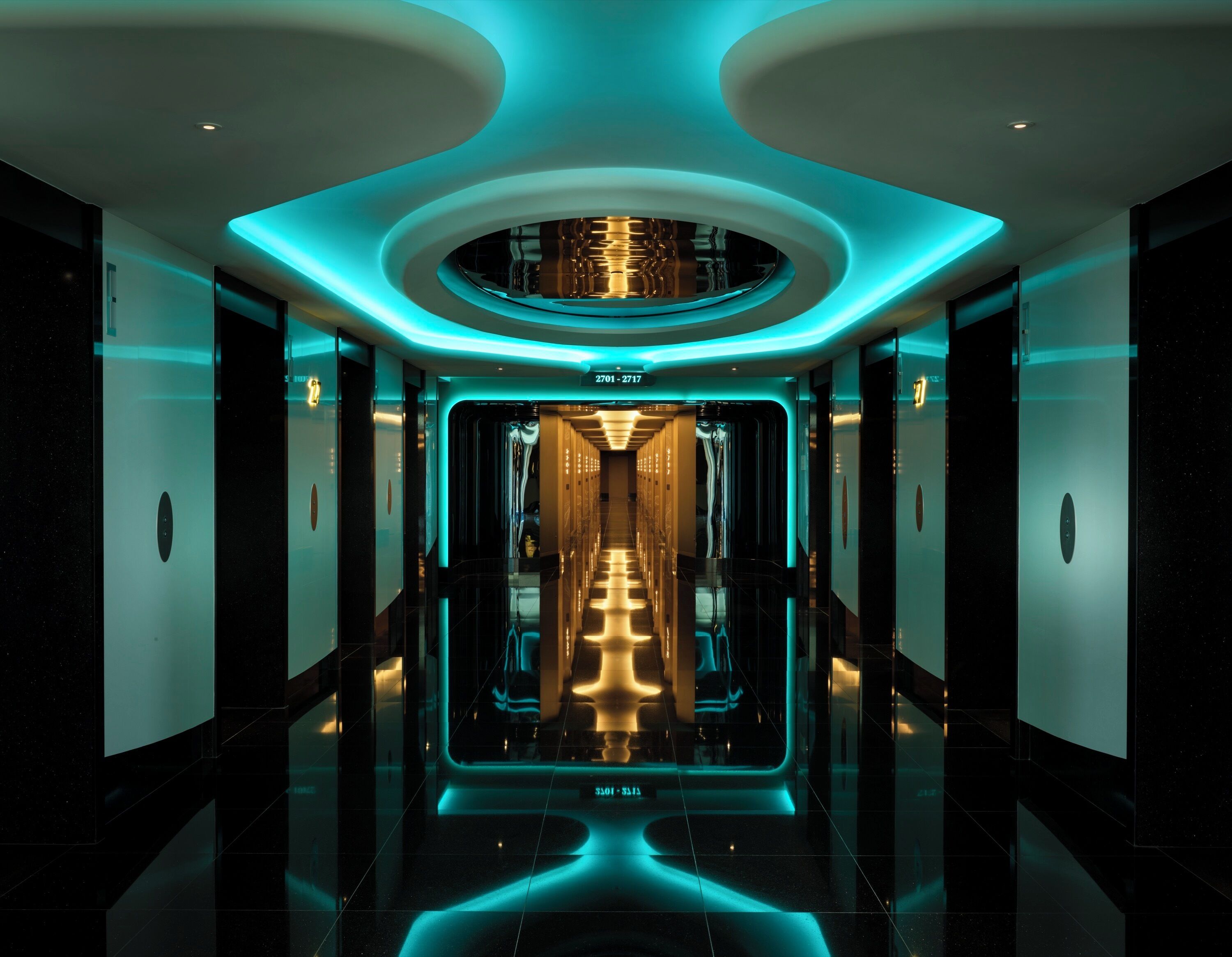 A modern, well-lit hallway with a central reflective floor and a ceiling with circular light fixtures.