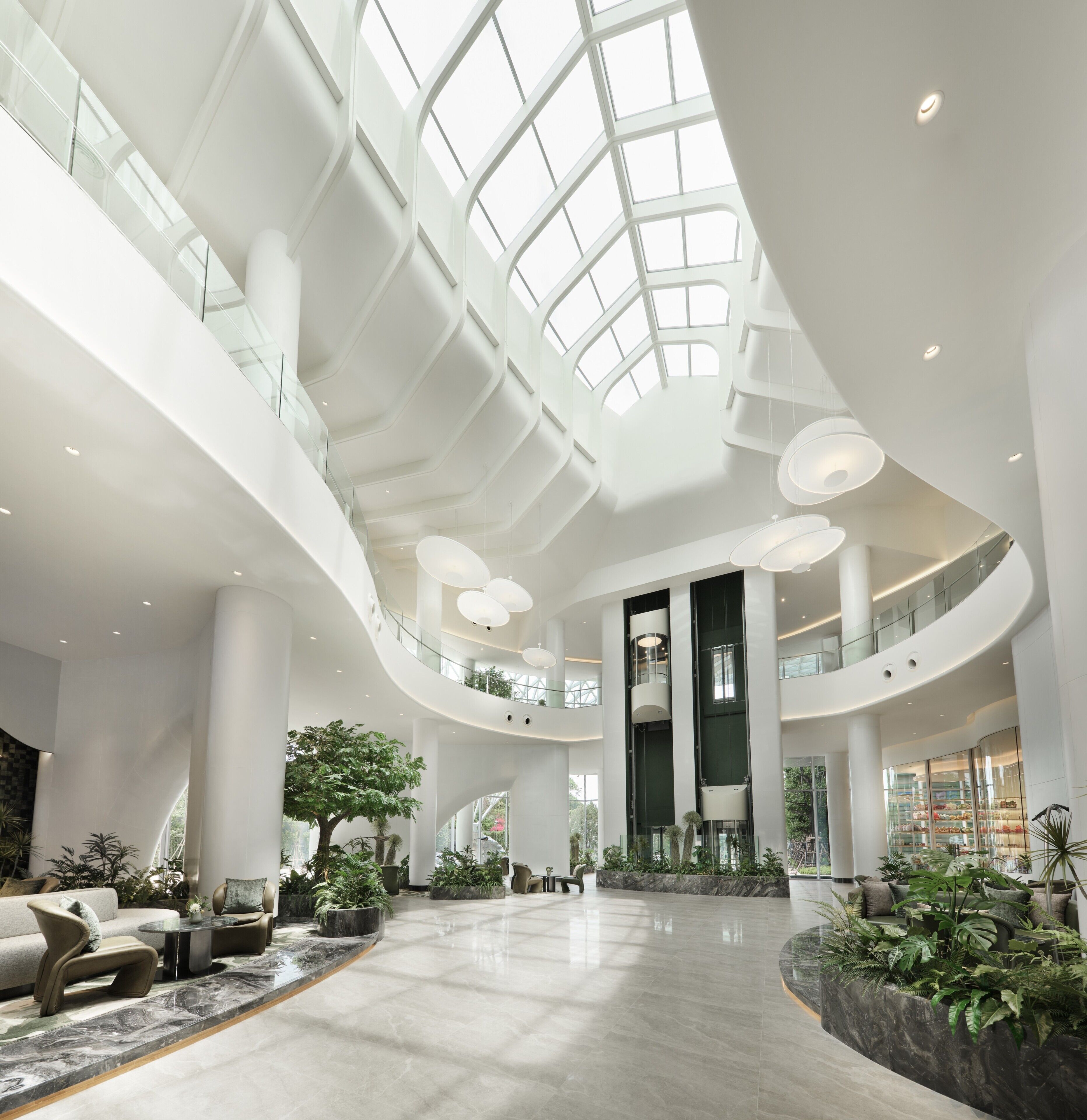 A spacious interior with a high ceiling, multiple levels, and a central atrium with seating and plants.