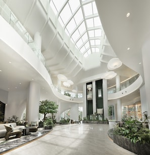 Un intérieur spacieux avec un plafond haut, de nombreux niveaux et un atrium central agrémenté de sièges et de plantes.