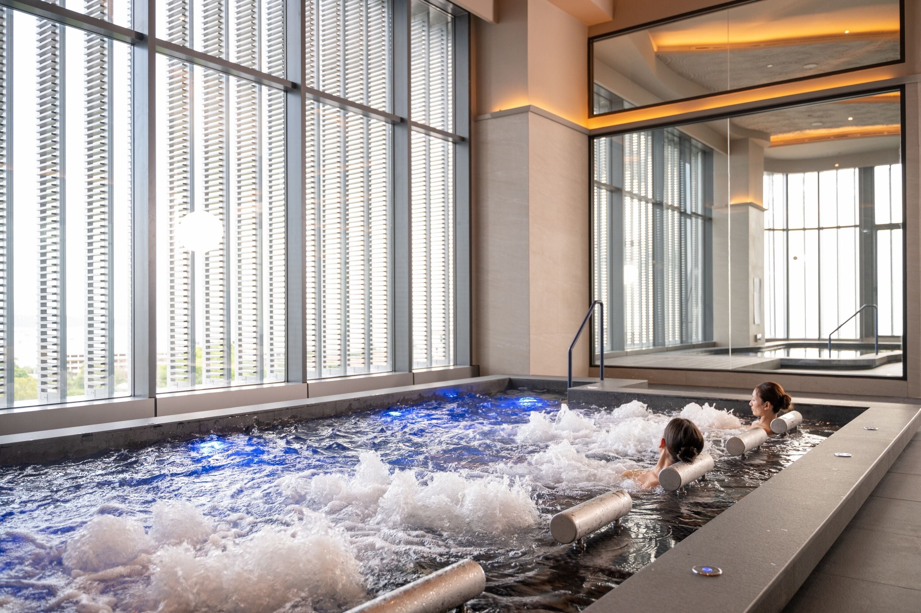 A spa area with a hot tub, large windows, and a view of the city.