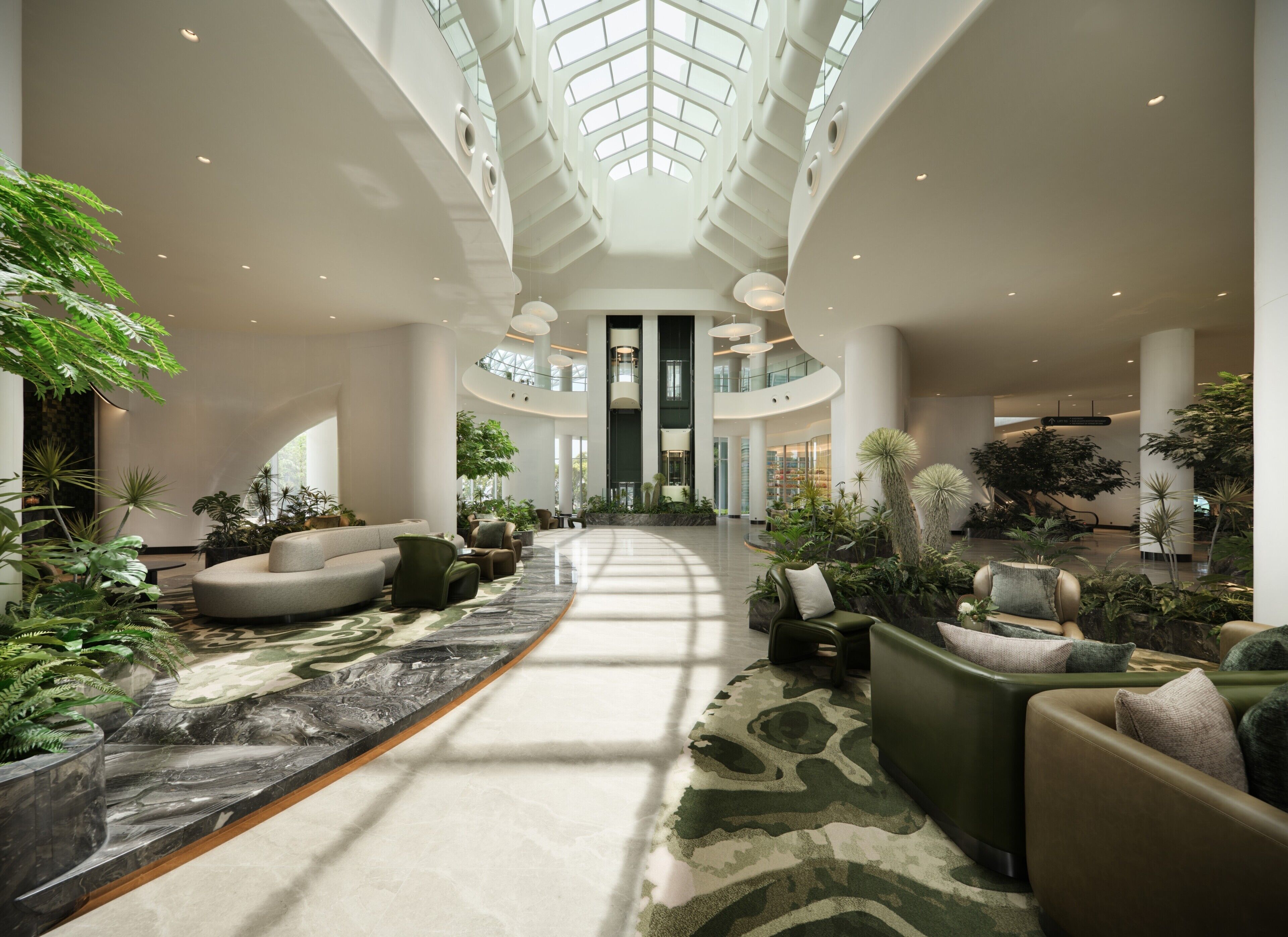 A spacious lobby with a central walkway, seating areas, and a high ceiling with skylights.