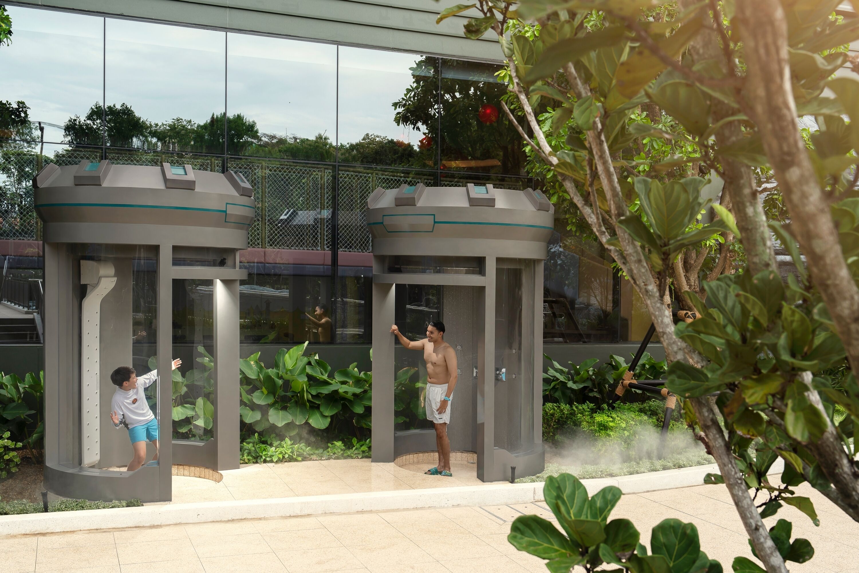 A modern building with a glass facade, a water feature, and a seating area with planters.