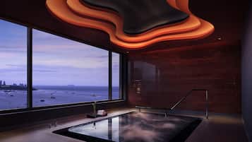 Un moderno cuarto de spa con un ventanal grande, piso con calefacción y un diseño de techo original.