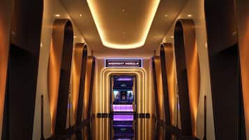 A modern elevator with a sign reading 'MIDNIGHT NEBULA' and a purple-lit interior.