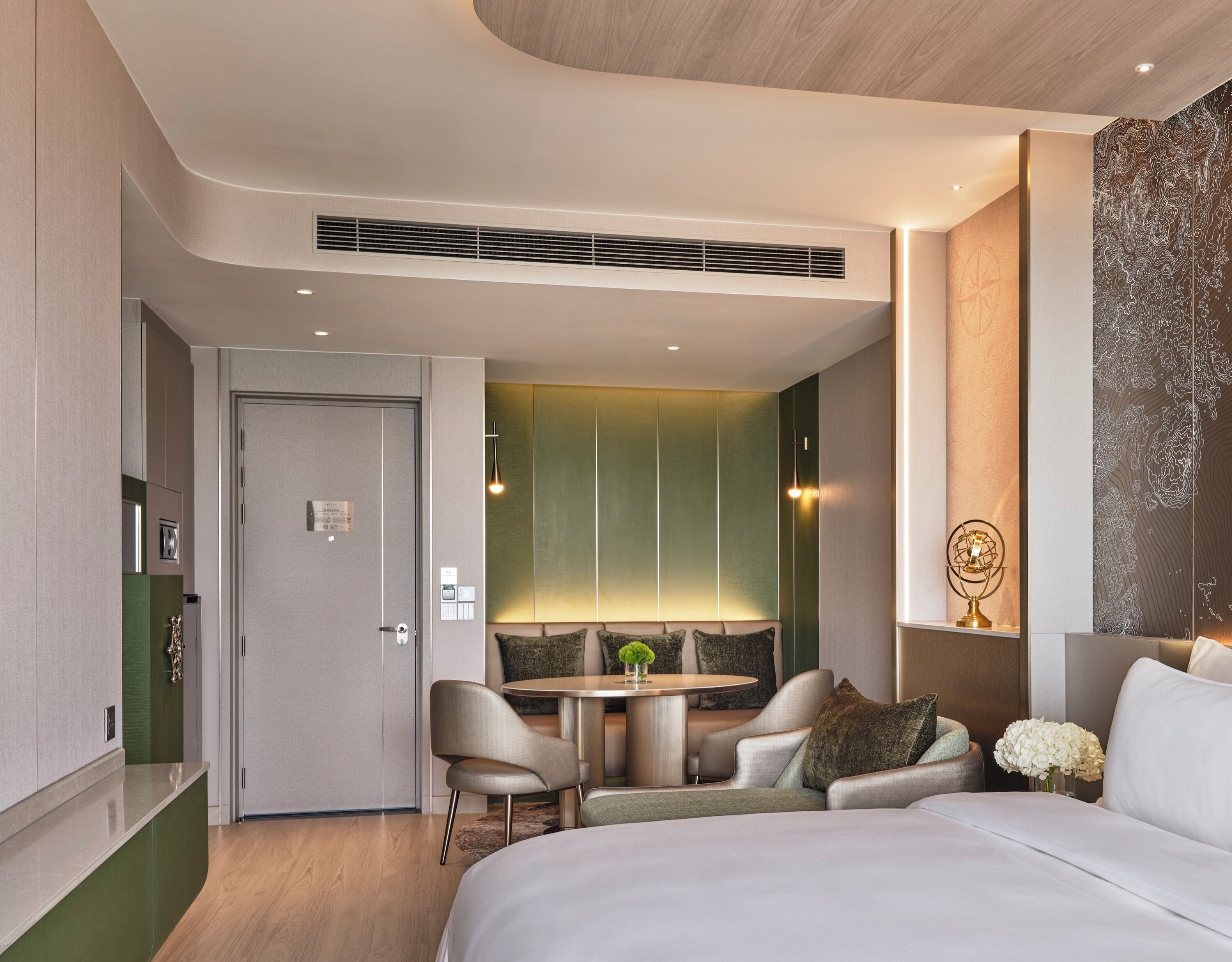 A modern hotel room with a bed, seating area, and a dining table.
