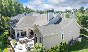 Ein Wohnhaus mit Terrasse, einer überdachten Sitzgelegenheit im Freien und einem gepflegten Rasen.