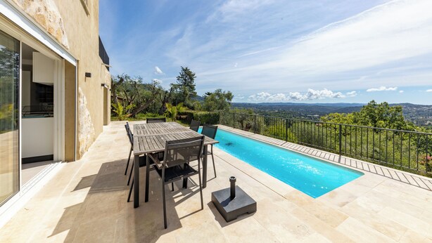 Ein Poolbereich mit Tisch und Stühlen, einem Grill und Blick auf die Landschaft.