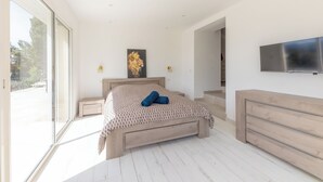 Ein Schlafzimmer mit einem Bett, einem Fernseher, einem Gemälde und einem Fenster.