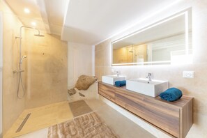 Une salle de bain moderne avec une douche à parois de verre, deux vasques, un meuble-lavabo en bois et un grand miroir.