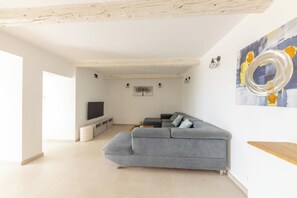 A modern living room with a grey sectional sofa, a flat-screen TV, and abstract wall art.