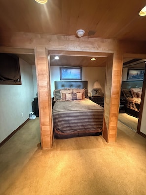 Une chambre à coucher comprenant un lit, une tête de lit, une table de chevet, une lampe et un tableau encadré accroché au mur.