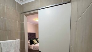 Une petite salle de bain comprenant des toilettes, un porte-serviettes et un espace douche.