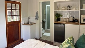 Une cuisine de taille réduite, équipée d’un évier, d’un réfrigérateur et d’une porte en bois.