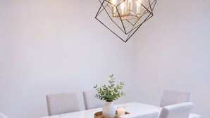 Ein Esstisch mit sechs Stühlen, einem geometrischen Kronleuchter und einer kleinen Pflanze als Tischdeko.