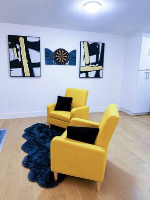 A room with two yellow armchairs, a black furry rug, and abstract art on the walls. - Stylish 3-bedroom Full House Near Magnetic Hill (Moncton)