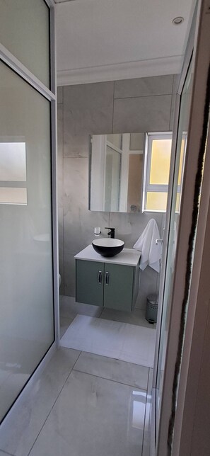 A modern bathroom with a large mirror, a sink, and a cabinet. - Luxury guest Apartment Fully furnished with all amenities (Pretoria)