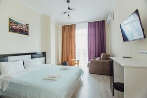 A hotel room with a bed, a desk, a chair, a television, and a window with curtains. - Hotel Mimino & Restaurant (Batumi)