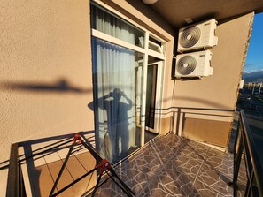 A balcony with a glass door, two air conditioning units, and a tiled floor. - Hotel Mimino & Restaurant (Batumi)