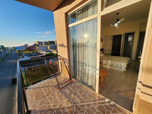 A balcony with a glass door leading to a bedroom with a bed and a small table. - Hotel Mimino & Restaurant (Batumi)