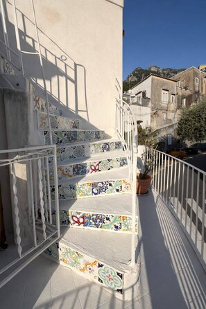 Un escalier aux carreaux colorés menant à un balcon doté d’une balustrade blanche.