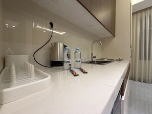 A modern kitchen with a sink, kettle, and water bottles on the counter. - 104 JRE apartment with stunning boulevar (Amman)