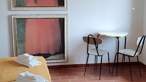 Una habitación con cama, una mesa con sillas y tres cuadros en la pared.